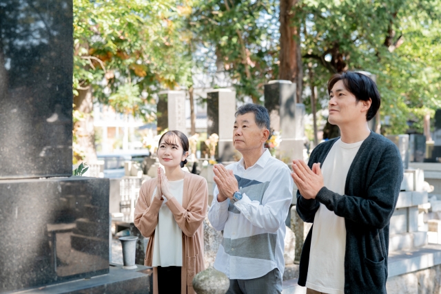 墓地で祈りを捧げる家族の様子。先祖への感謝と家族の絆を表す光景