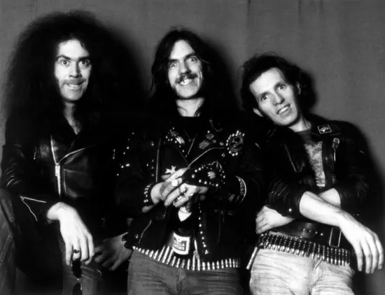 モノクロ写真に写るモーターヘッドの3人のメンバー。中央にレミー・キルミスター、その左にフィル・“フィルシー・アニマル”・テイラー、右に“ファスト”・エディ・クラークがいる。